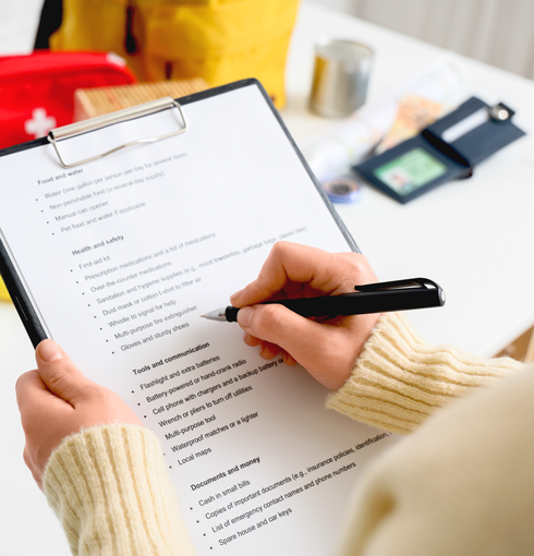 Young woman with check list of necessities for emergency backpack at home, closeup